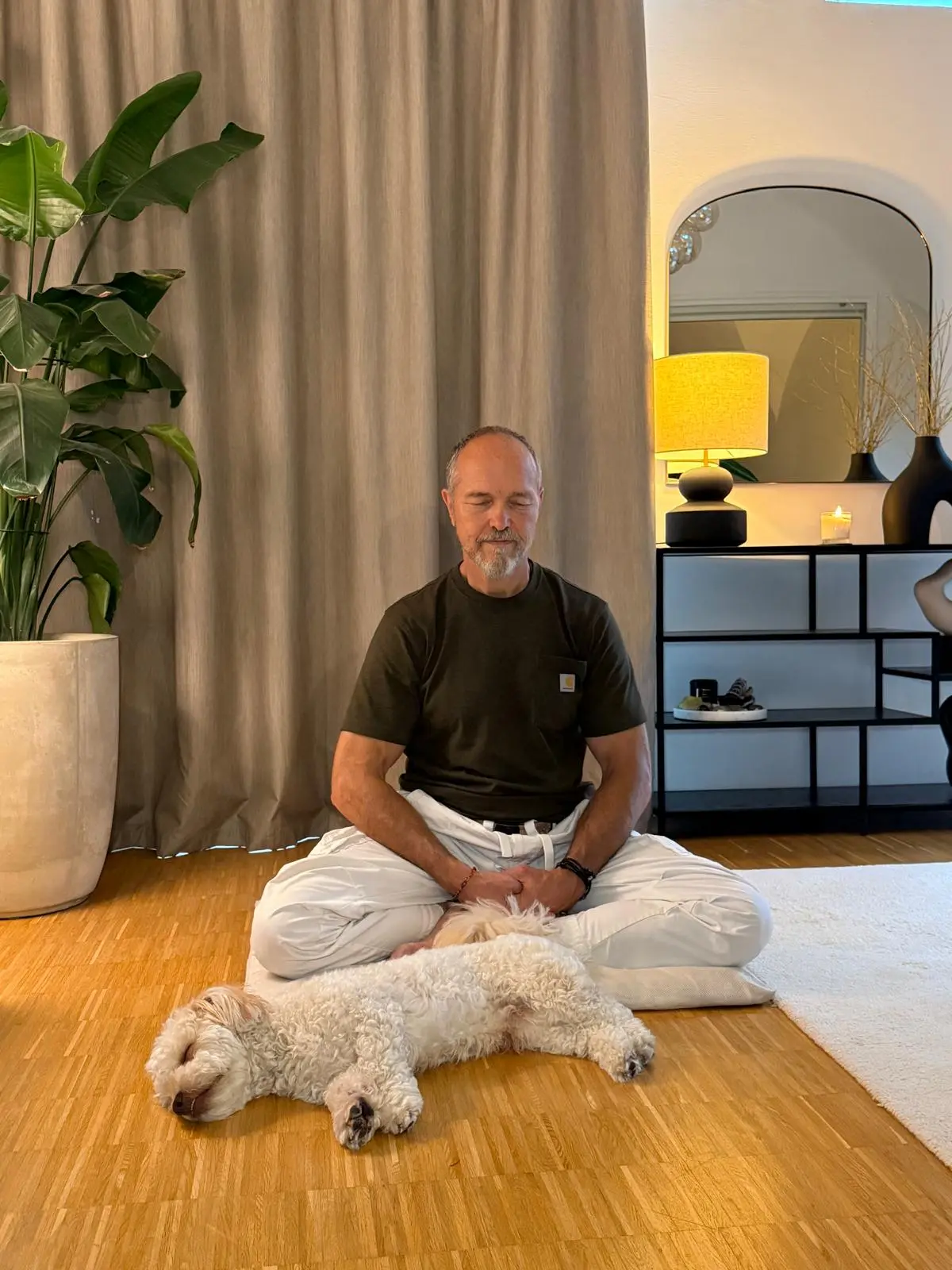 Dieter Schleier in Meditation zu Hause, sein Hund liegt neben ihm auf dem Boden