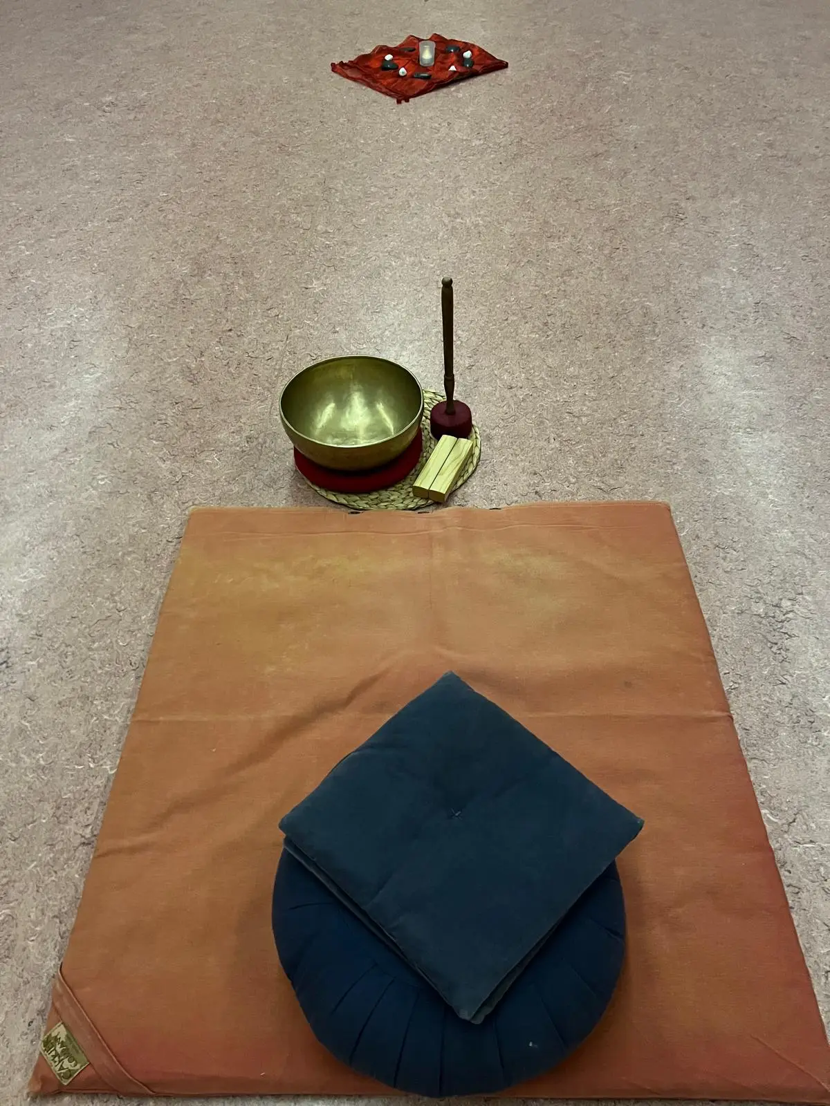 Meditationskissen auf einer Decke im Freien, daneben ein Buch über den Weg der Stille