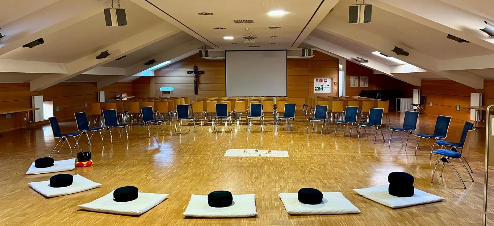 Vorbereiteter Meditationskreis: Matten und Kissen liegen im Kreis in einem hellen Saal